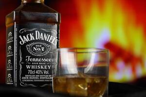 kiev, Ucraina - Maggio 4, 2022 Jack daniel originale alcool bottiglia su di legno tavolo con rosso camino foto