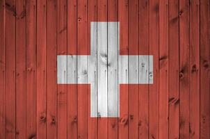Svizzera bandiera raffigurato nel luminosa dipingere colori su vecchio di legno parete. strutturato bandiera su ruvido sfondo foto