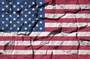 unito stati di America bandiera raffigurato nel dipingere colori su vecchio pietra parete avvicinamento. strutturato bandiera su roccia parete sfondo foto