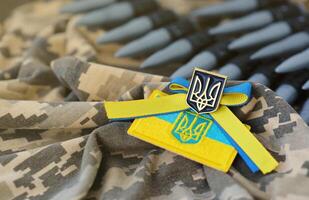ucraino simbolo e un' macchina pistola cintura su il camuffare uniforme di un' ucraino soldato. il concetto di guerra nel Ucraina, patriottismo e proteggere il tuo nazione a partire dal occupanti foto