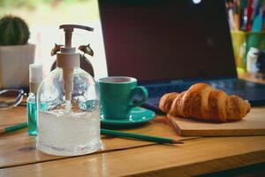 donne utilizzando il computer portatile Lavorando e pulito mani con alcool bevanda caffè tazza caldo a casa foto