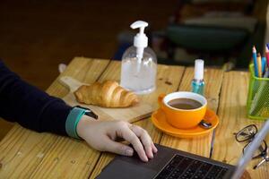 donne utilizzando il computer portatile Lavorando e pulito mani con alcool bevanda caffè tazza caldo a casa foto