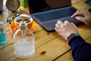 donne utilizzando il computer portatile Lavorando e pulito mani con alcool bevanda caffè tazza caldo a casa foto