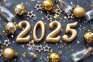 il d'oro figure 2025 fatto di candele su un' nero pietra ardesia sfondo siamo decorato con un' festivo arredamento di stelle, paillettes, abete rami, palle e ghirlande. saluto carta, contento nuovo anno. foto