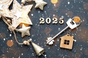 Casa chiave con portachiavi Villetta su festivo nero sfondo con stelle, luci di ghirlande. nuovo anno 2025 di legno lettere, saluto carta. Acquista, costruzione, trasloco, mutuo, assicurazione foto