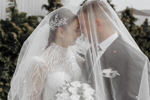 il sposa nel un elegante vestito con un' mazzo e il sposo nel un' classico completo da uomo siamo a piedi nel il giardino, Tenere mani. foto