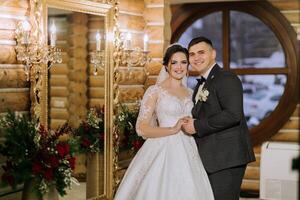 ritratto di un' contento sposa e sposo nel il sala di un' moderno Hotel vicino un' specchio. inverno nozze. foto