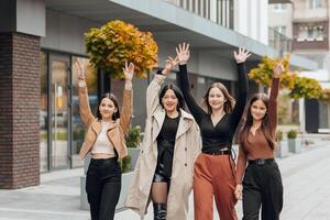 gruppo di sorridente e contento adolescenziale amici indossare casuale Abiti la spesa tempo insieme, in posa e parlando con ogni altro vicino Università edificio su autunno giorno. foto