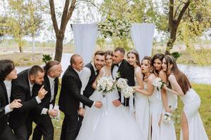 lunghezza intera ritratto di il Novelli sposi e loro amici a il nozze. il sposa e sposo con damigelle d'onore e amici di il sposo siamo avendo divertimento e gioia a il nozze. foto