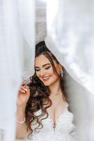 un' meraviglioso bellissimo ritratto di un' giovane sposa. bellissimo sposa con nozze trucco e gioielleria ghirlanda su lungo Riccio capelli. nozze foto modello con Marrone occhi nel un' bellissimo interno.