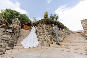 angolo ampio foto di il sposa e sposo su il passaggi contro il sfondo di pietra muri. gratuito spazio.