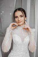 moda ritratto di un' bellissimo sposa nel un' lussuoso nozze vestito con pizzo e cristalli nel un Arabo interno stile. brunetta contento donna indossare nozze vestito con nozze trucco e acconciatura. foto