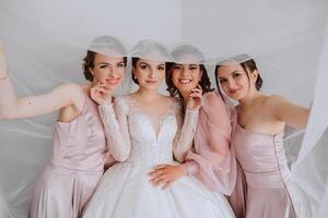 amici rallegrarsi con il sposa nel il mattina. essi prendere immagini, Sorridi, Aiuto il sposa allacciare sua vestire. foto