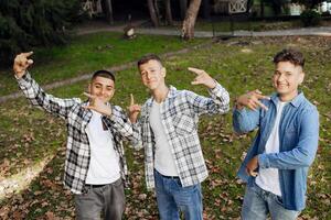 tre adolescenziale ragazzi, in posa nel natura, gioire, in esecuzione e avendo divertimento. adolescenziale compagne di classe siamo riposo contro il sfondo di un autunno foresta. foto