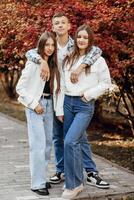 tre adolescenti di diverso sessi, in posa nel natura. adolescenziale compagne di classe siamo riposo contro il sfondo di un autunno foresta. foto