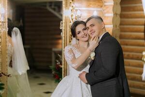 ritratto di un' contento sposa e sposo nel il sala di un' moderno Hotel vicino un' specchio. inverno nozze. foto