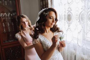 mattina di il sposa. il della sposa domestica di onore aiuta il sposa pizzo su sua vestire, allacciare pulsanti su il vestito o maniche. amiche Aiuto il sposa allacciare sua vestito foto