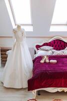 Camera da letto interno con nozze vestito preparato per il cerimonia. un' bellissimo lussureggiante nozze vestito su un' indossatrice nel un' Hotel camera. foto