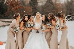 il sposa e sua damigelle d'onore posa Tenere mazzi di fiori e guardare a il sposa. inverno nozze foto