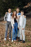 quattro adolescenti di diverso sessi, in posa nel natura. adolescenziale compagne di classe siamo riposo contro il sfondo di un autunno foresta. foto