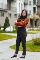 verticale foto. bellissimo spensierato giovane adolescenziale ragazza nel casuale Abiti. ritratto di un' bellissimo ragazza contro il sfondo di natura con un' sfocato sfondo. foto