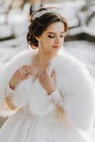 ritratto di un' bellissimo sposa con un' nozze mazzo di fiori, attraente donna nel un' nozze vestito con un' lungo velo. contento sposa donna. sposa con nozze trucco e pettinatura. inverno nozze foto