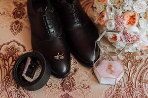 Uomini Accessori, sposo dettagli piatto posizione. nero scarpe, oro nozze anelli, un' nozze mazzo di fiori foto