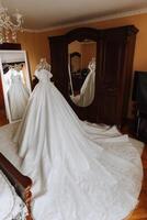 Camera da letto interno con nozze vestito preparato per il cerimonia. un' bellissimo lussureggiante nozze vestito su un' indossatrice nel un' Hotel camera. foto