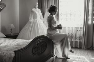 un' contento sposa è preparazione per sua lussuoso nozze nel un' Hotel camera, con un' nozze vestito su un' indossatrice qui vicino. ritratto di un' donna con alla moda capelli, trucco e un' Sorridi nel un' condimento abito. foto