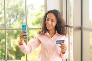 bella donna latina che utilizza smartphone con carta di credito