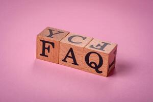 il iscrizione FAQ fatto su di di legno cubi su un' pianura sfondo foto