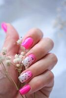Da donna mani con un' alla moda rosa manicure hold secco fiori nel loro mani. primavera - estate chiodo design foto