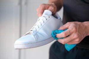 un' uomo pulisce bianca scarpe da ginnastica a partire dal sporco foto