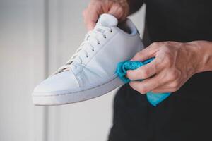 un' uomo pulisce bianca scarpe da ginnastica a partire dal sporco foto