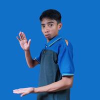 sorpreso asiatico uomo con tutti e due mani formatura un' fotocopia nel il mezzo, indossare un' blu maglietta. sfondo isolato blu colore foto
