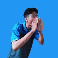 asiatico uomo urlando indossare blu maglietta, isolato blu sfondo. foto