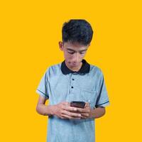 asiatico uomo sorpreso guardare a il suo inteligente Telefono isolato giallo sfondo. foto