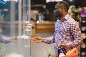 africano americano uomo shopping nel un' supermercato foto