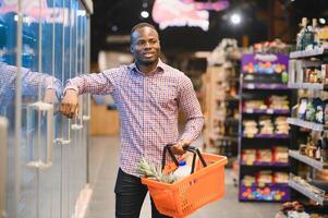 attraente africano americano uomo shopping nel un' supermercato foto