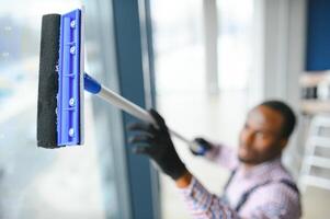 contento maschio lavoratore pulizia bicchiere con seccatoio e spray bottiglia foto