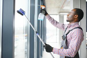 contento maschio lavoratore pulizia bicchiere con seccatoio e spray bottiglia foto