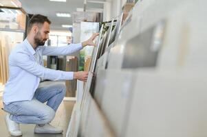 giovane uomo la scelta piastrelle a edificio mercato foto