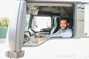 giovane indiano camion autista seduta dietro a timone ruota nel un' cabina foto
