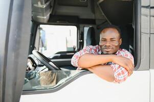camion autista uomo africano americano muscolare sorridente, nel a lungo attività commerciale mezzi di trasporto e consegna foto