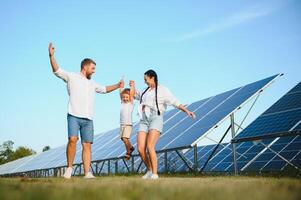 il concetto di verde energia. contento famiglia a piedi e avendo divertimento nel solare pannello campo. verde energia. foto