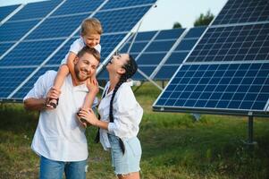 giovane famiglia con un' piccolo bambino nel sua braccia su un' sfondo di solare pannelli. un' uomo e un' donna Guarda a ogni altro con amore. solare energia concetto. foto