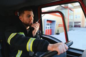 pompiere utilizzando Radio impostato mentre guida fuoco camion foto