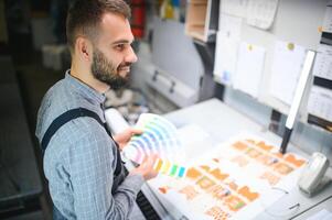 tipografo in piedi con colore campioni a il stampa produzione foto