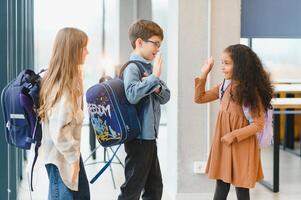 gruppo di elementare scuola bambini nel un' scuola corridoio foto