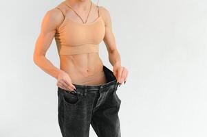donna mostrando risultato dopo peso perdita indossare su vecchio jeans su grigio sfondo foto